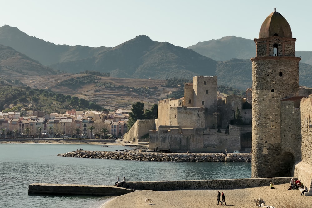 a stone building with a domed roof by a body of water