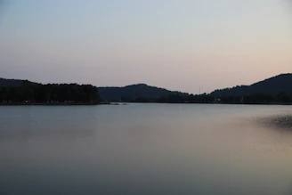 A serene sunrise over a quiet mountain lake, reflecting soft pastel colors.