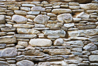 A sturdy retaining wall built with natural rock, blending seamlessly into a mountain landscape.