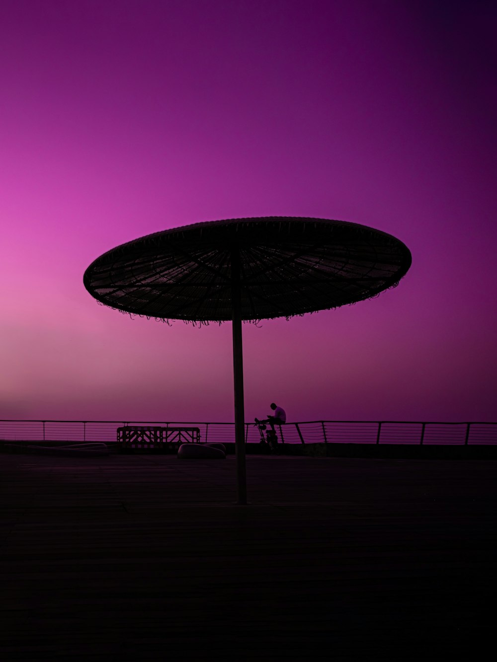 a person riding a bicycle under an umbrella at night