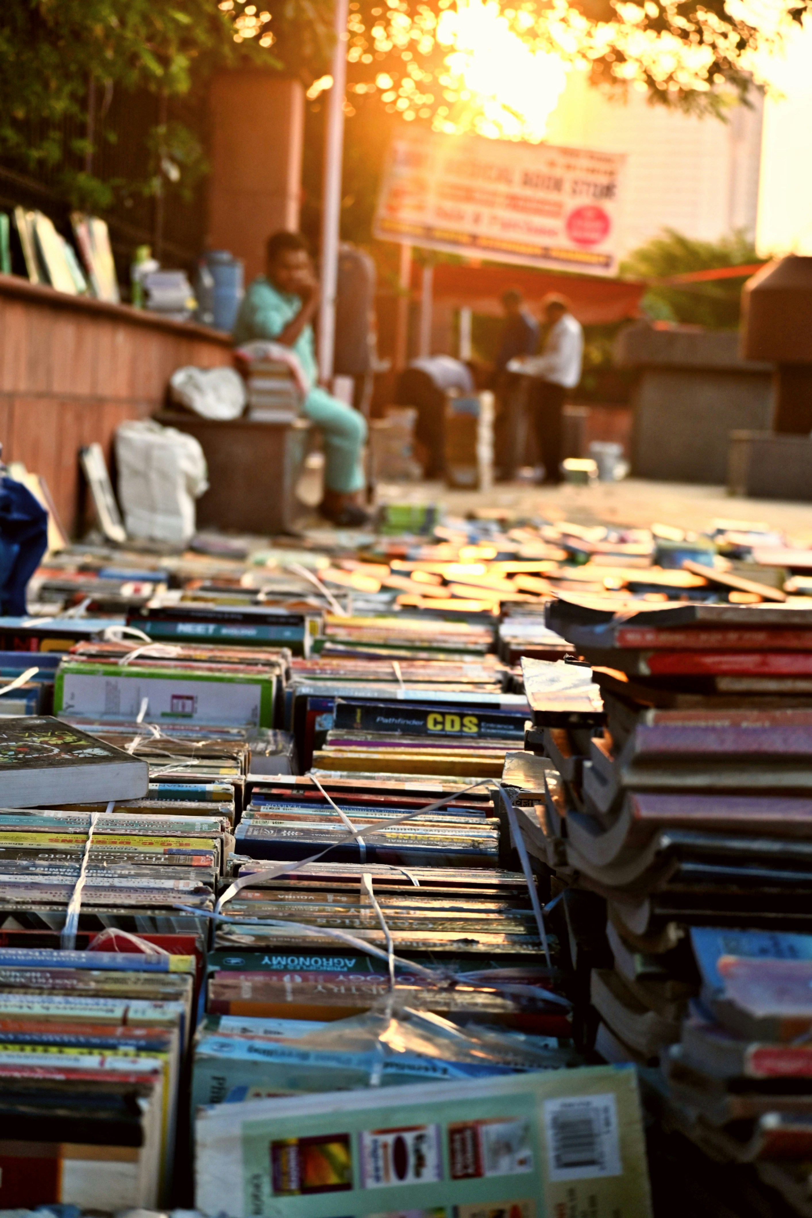 Stacked books on wooden surface, warm golden afternoon light, peaceful reading nook