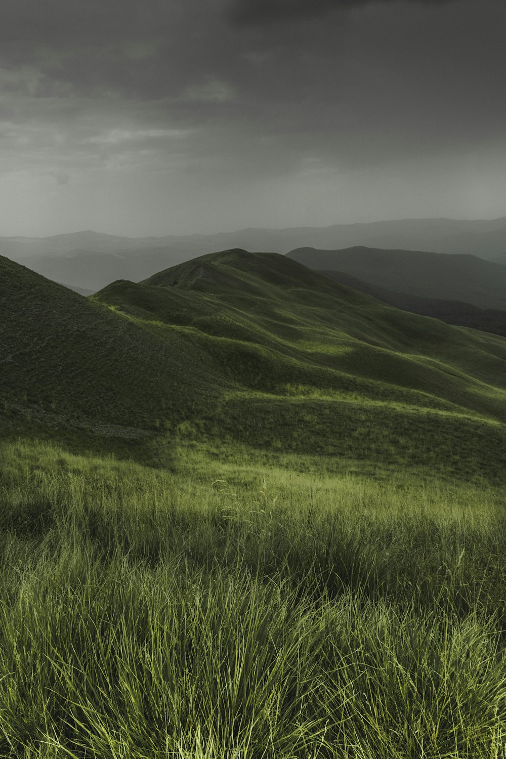 a grassy hill with a cloudy sky