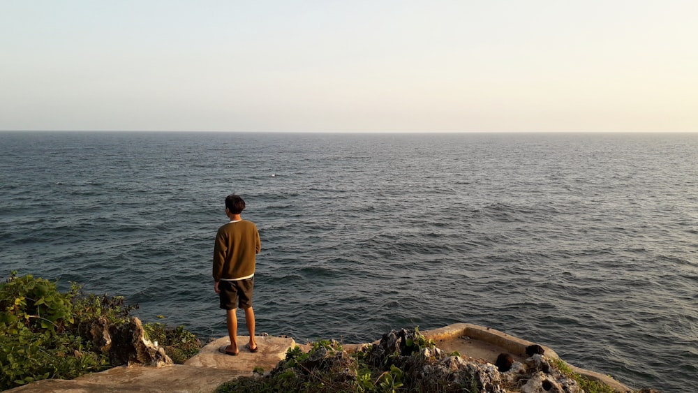 a man standing on a rock overlooking the ocean