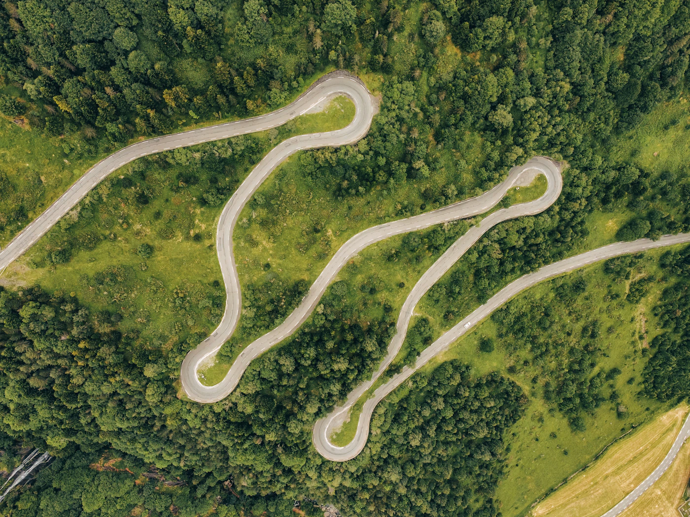 Vista cenital de una carretera con numerosas curvas de horquilla rodeada de bosque denso