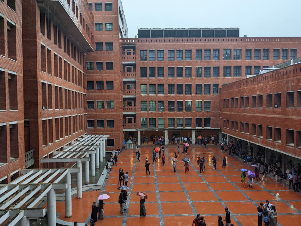 a group of people walking around a courtyard between brick buildings
