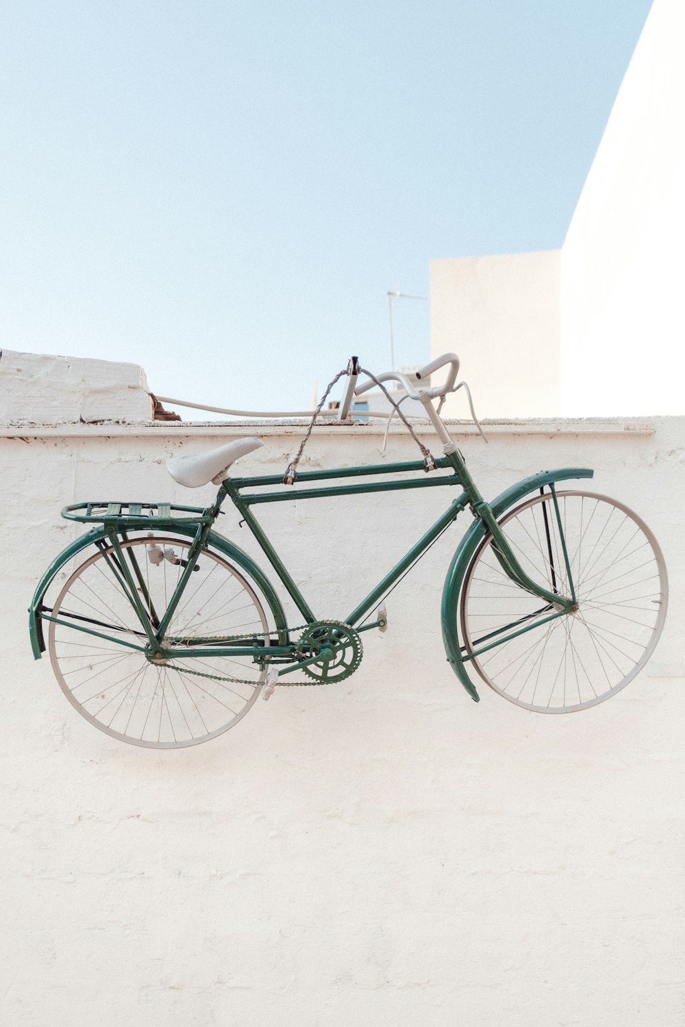 a green bicycle with a white wall behind it