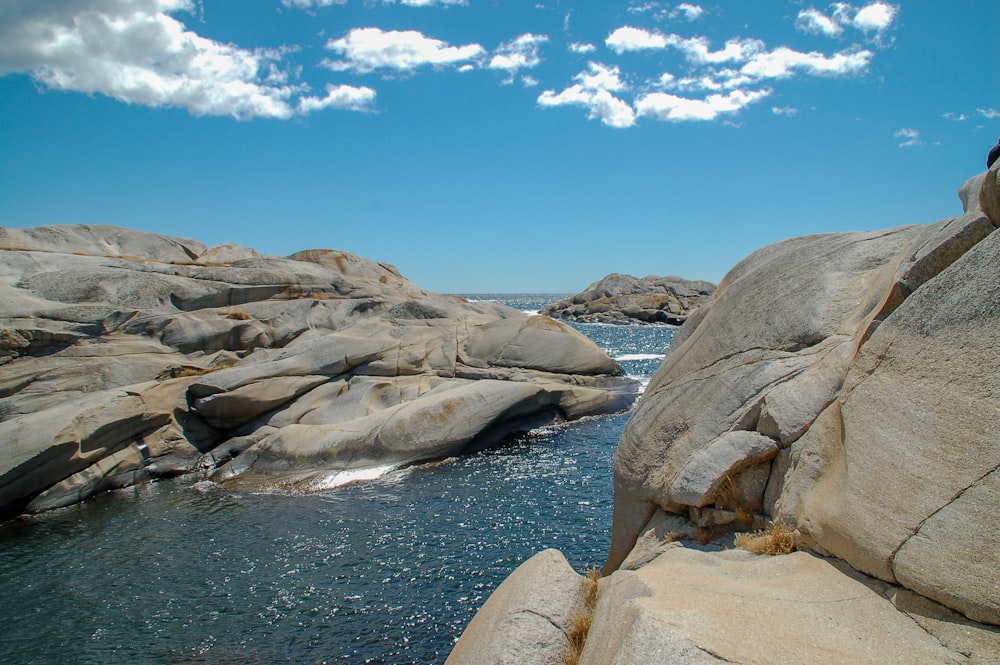 a rocky beach with a body of water in the background