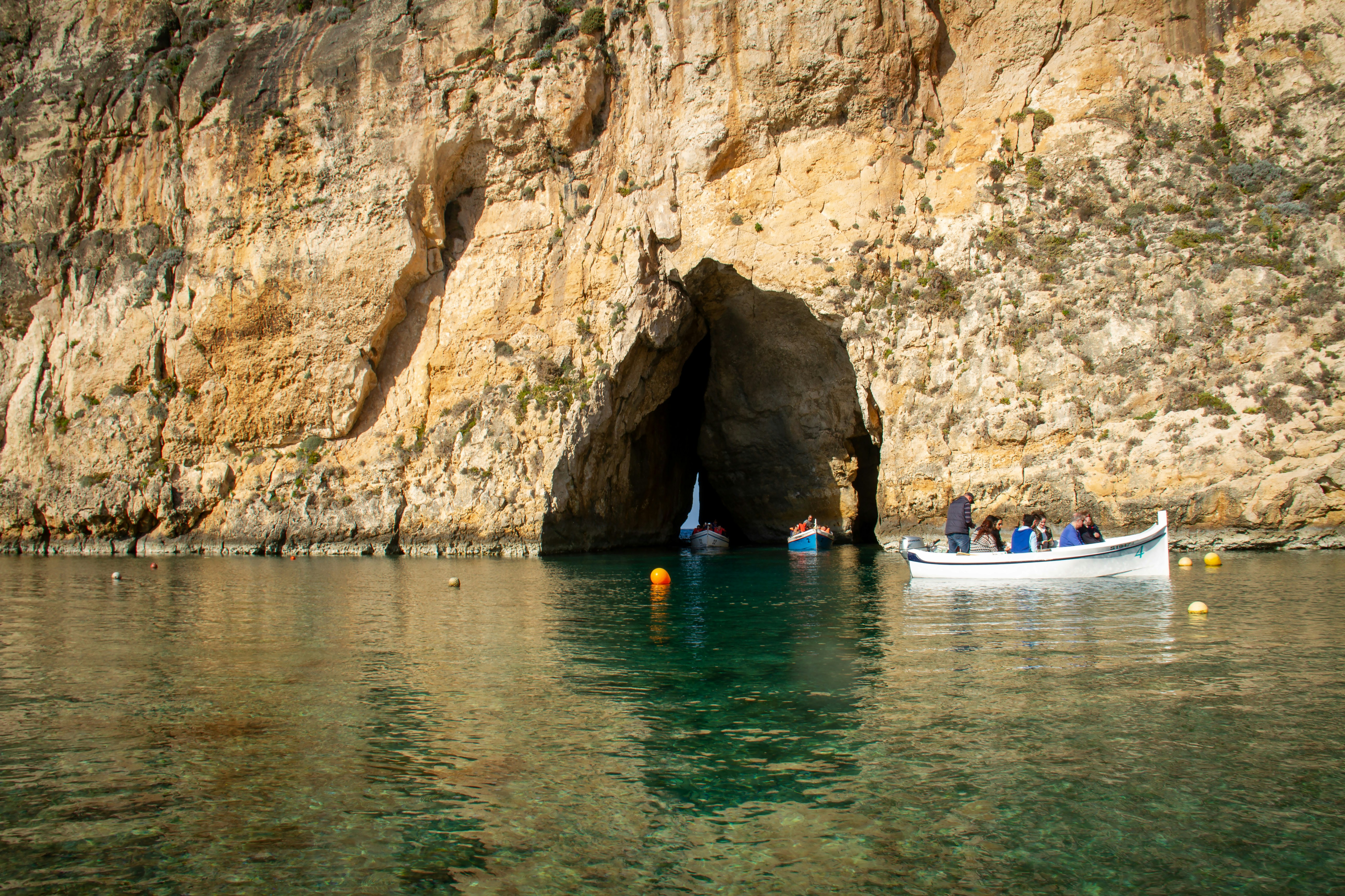 a boat in a body of water with a rock wall behind it