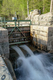 A sluice box set up along a creek, with water rushing through and gold settling inside.
