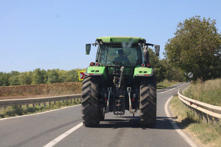 Tractor working on a rural road construction project surrounded by green fields.