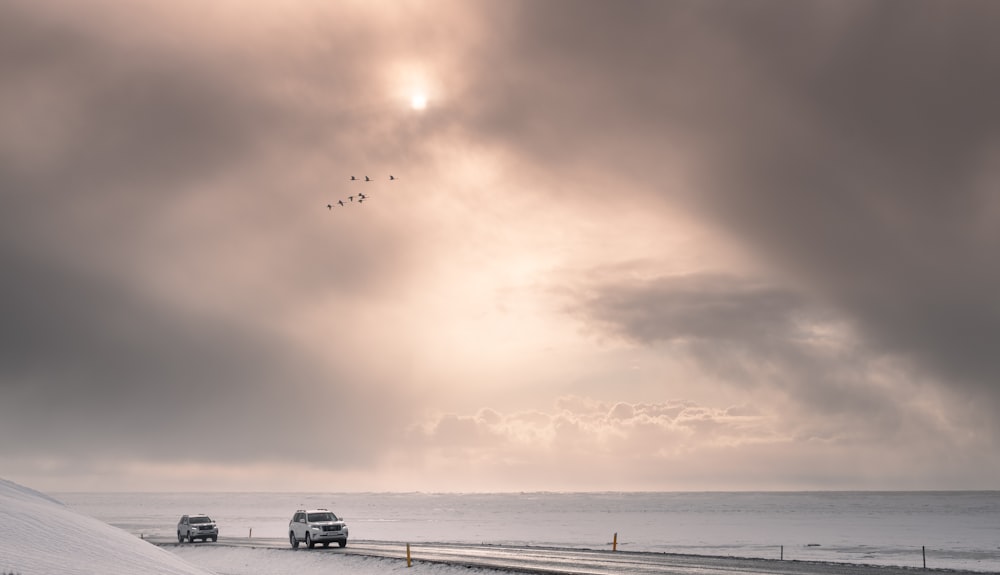 a group of cars parked on a beach under a cloudy sky