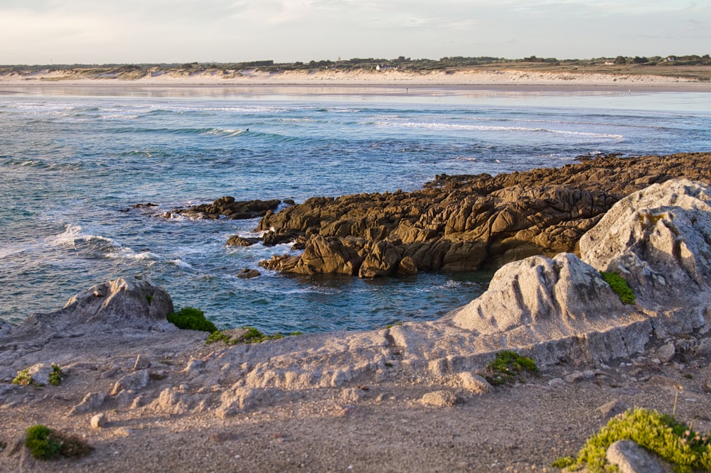 a rocky beach with a body of water in the background