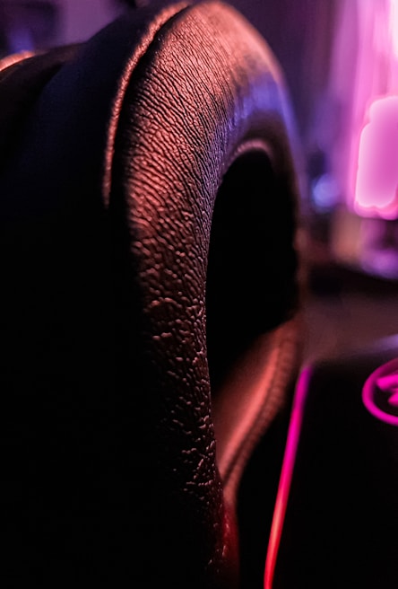 Close-up of a neon-lit hand gently touching a leather jacket, highlighting textures and shadows.