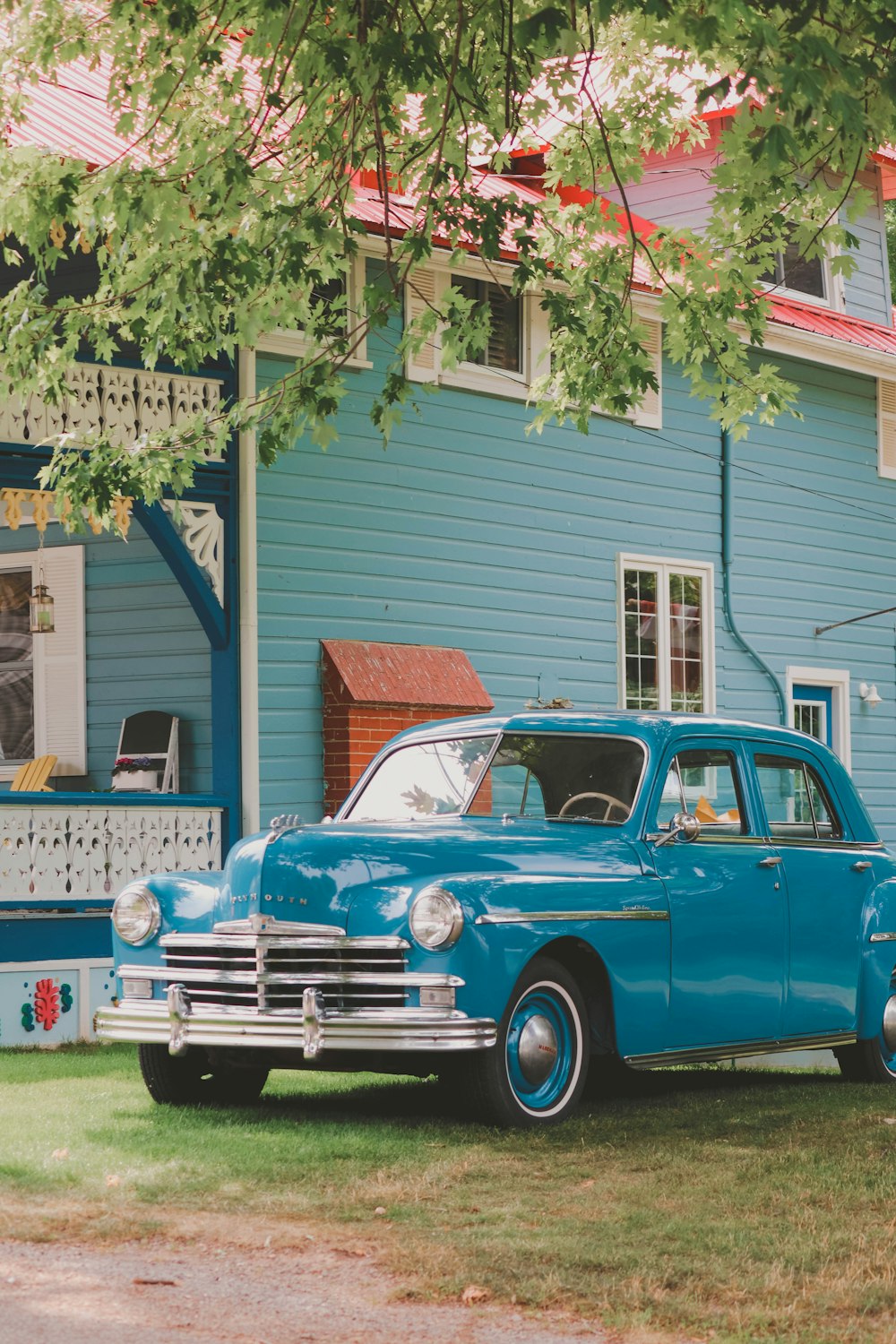 an old blue car parked in front of a house