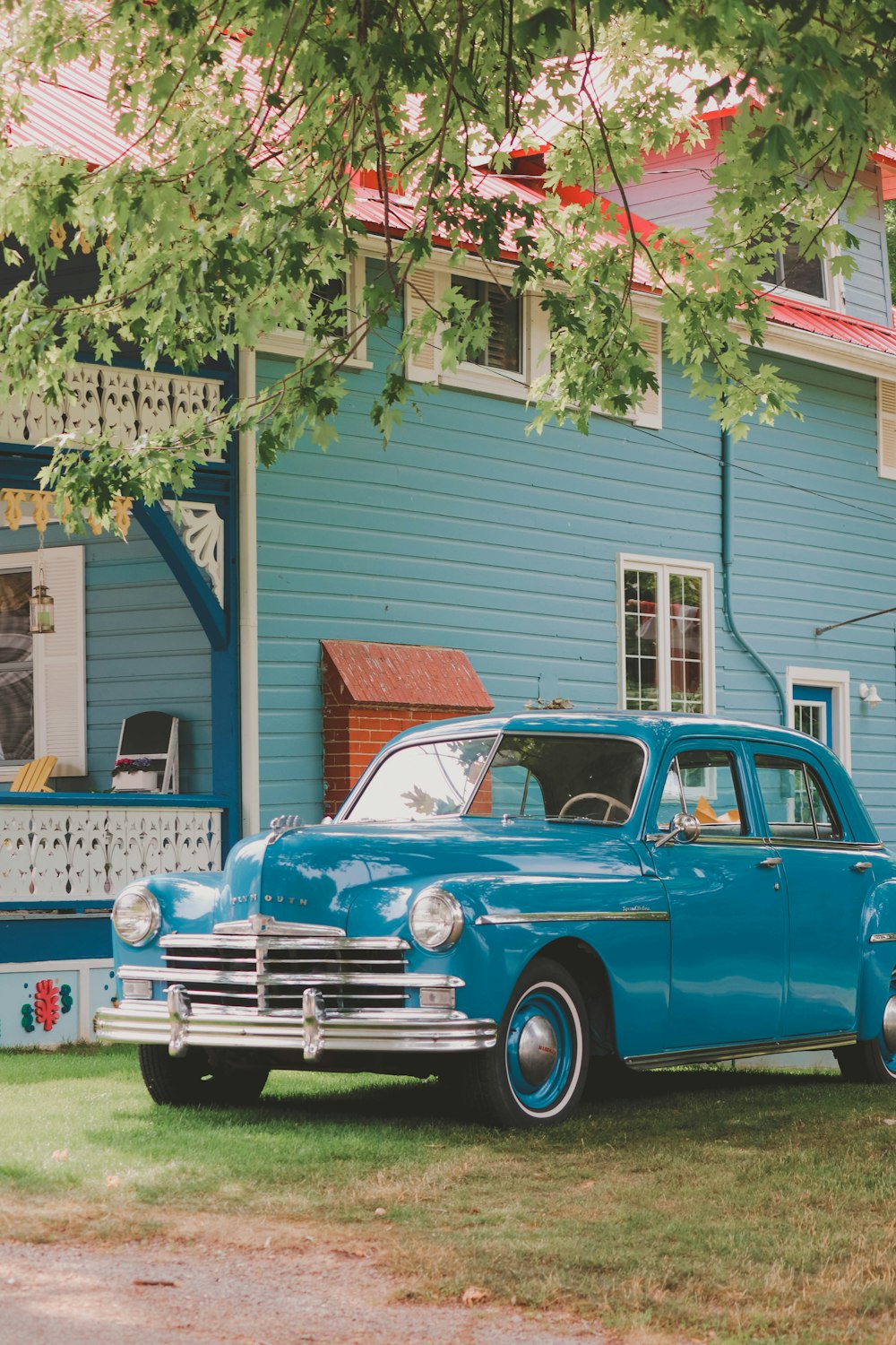 Un viejo coche azul aparcado frente a una casa