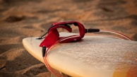 A close-up of a surfboard resting on the sandy beach.