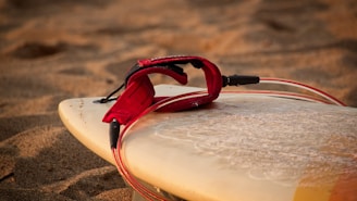 Close-up of a polished surfboard resting on the sand, reflecting sunlight.