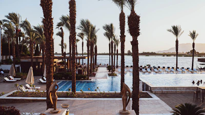a pool with palm trees and a beach in the background