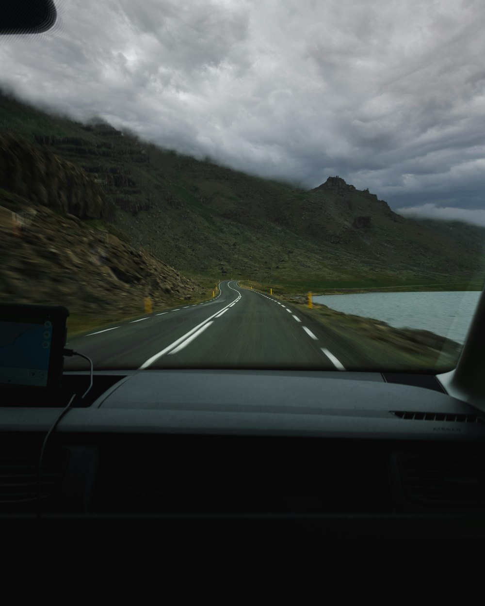 a road with a body of water and mountains in the background
