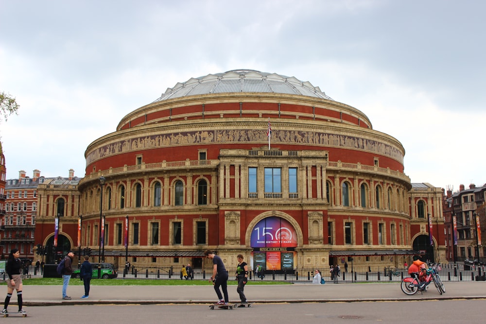 un gruppo di persone che fanno skateboard davanti a un grande edificio con la Royal Albert Hall sullo sfondo