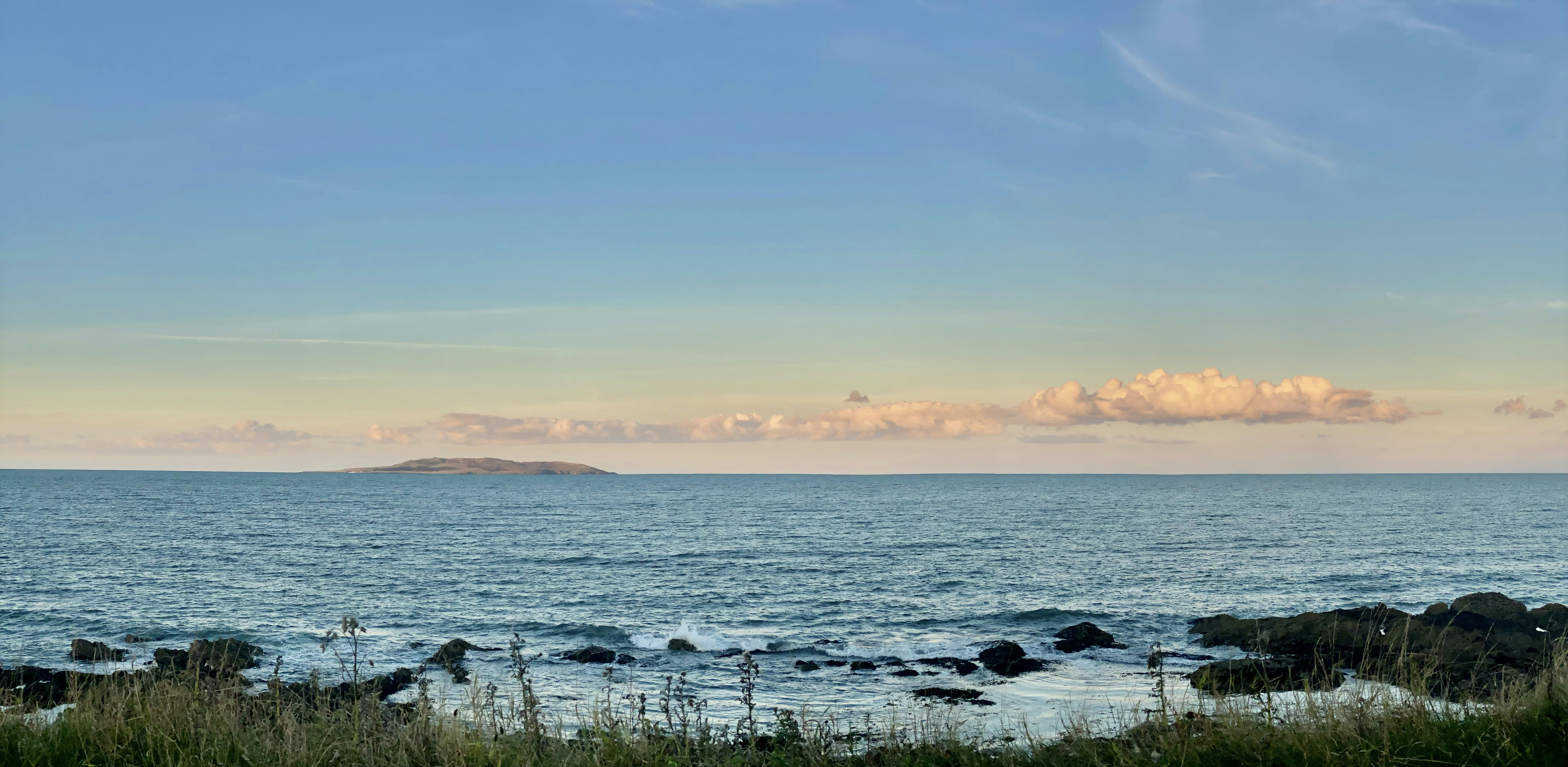 a body of water with rocks and grass on the side