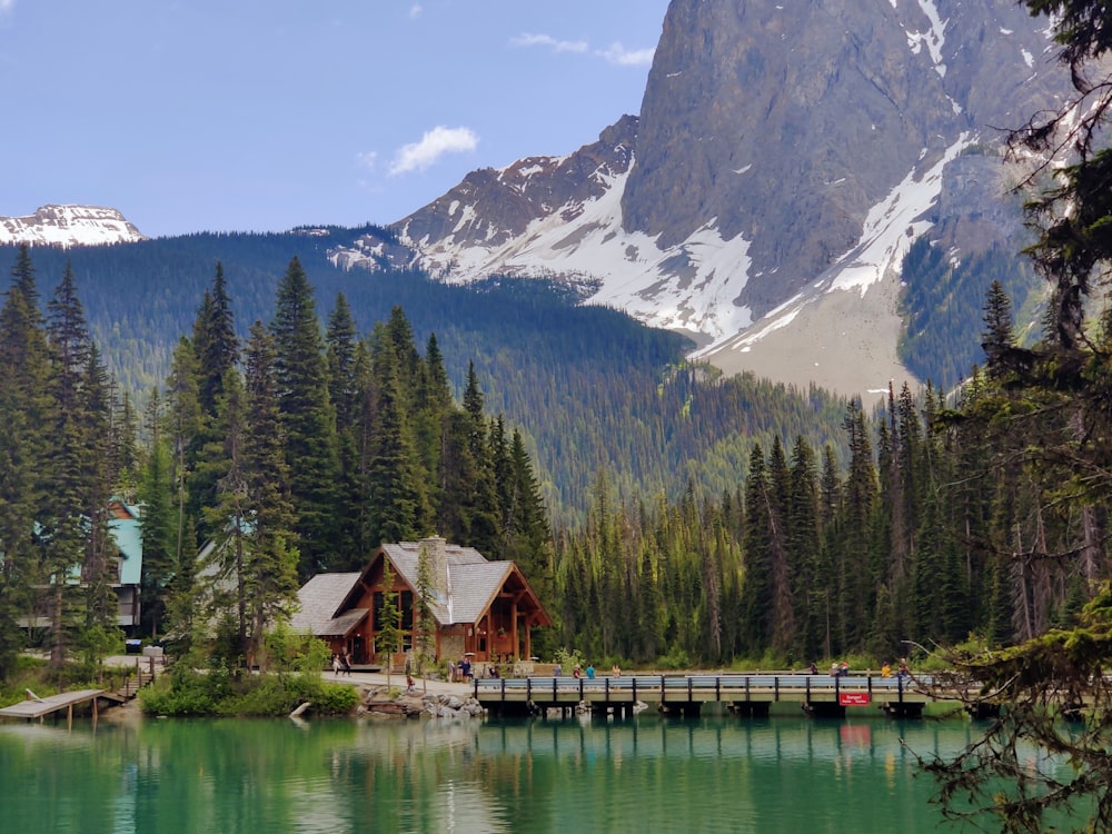 a house on a dock by a lake with trees and mountains in the background