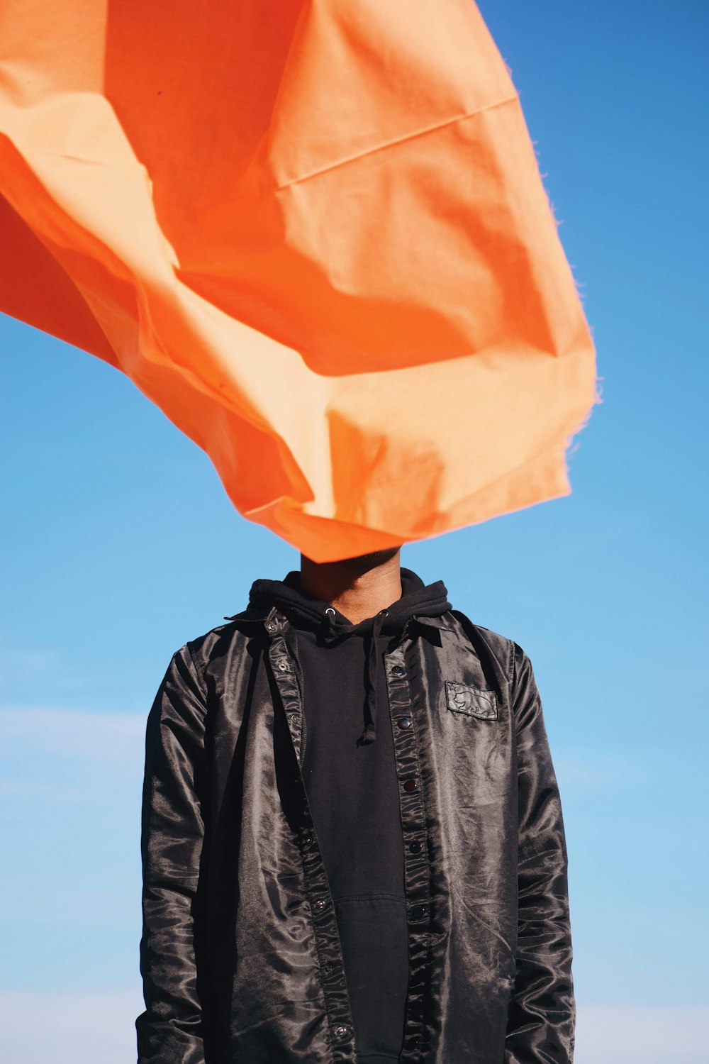 a person wearing a black jacket with a flag in the background