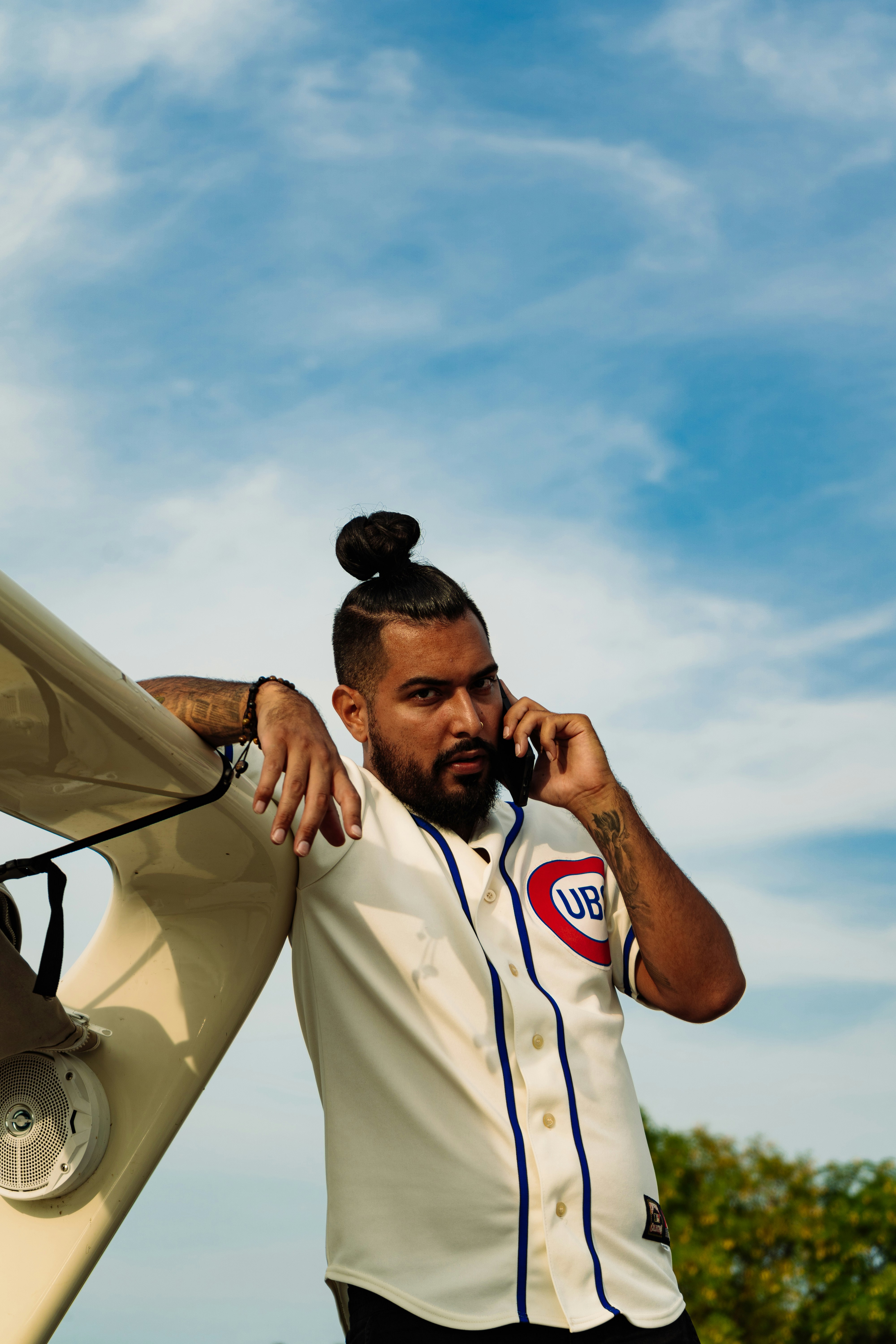 a man with a ponytail holding a phone to his ear