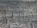 Abstract sculpture made from charred wood with visible cracks and folds.