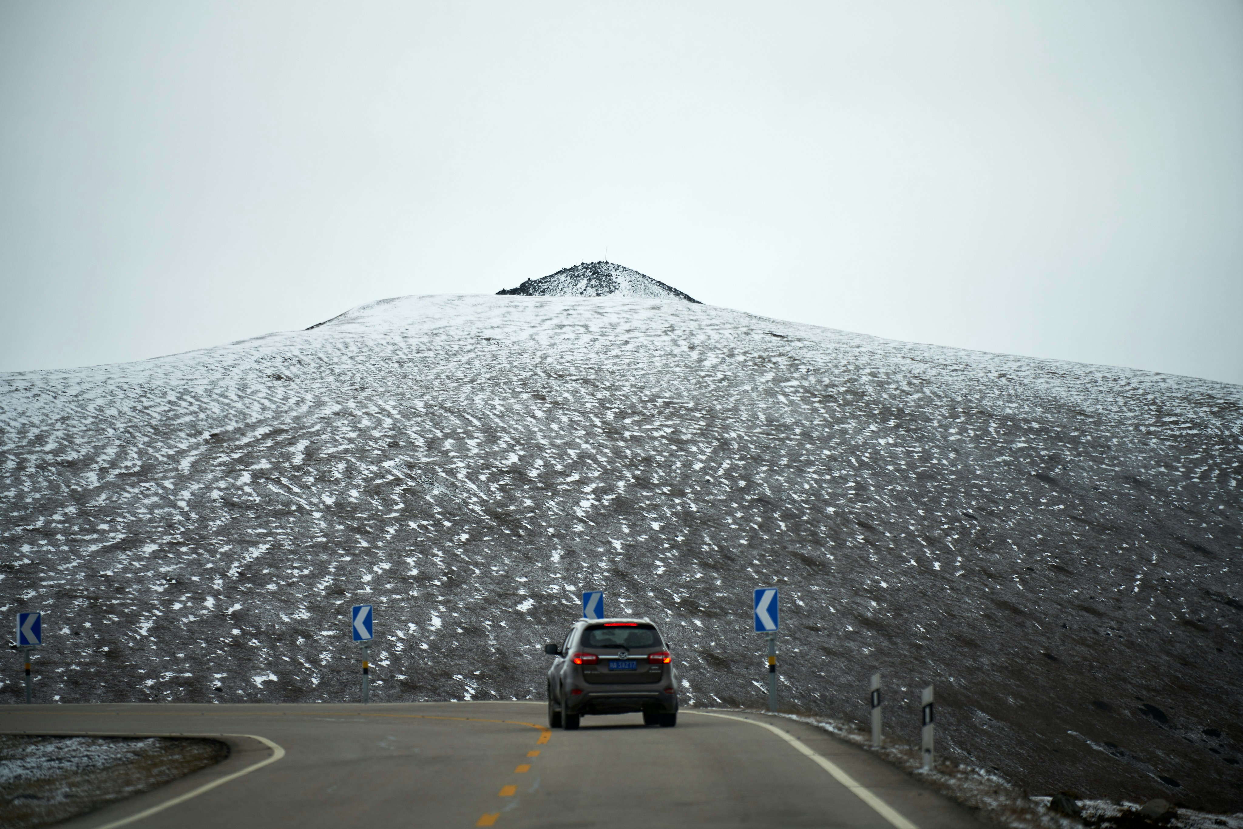 Un'auto che guida su una strada con la neve sul lato