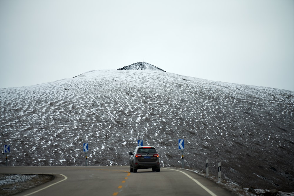 a car driving on a road with snow on the side