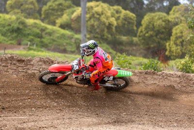 Dynamic shot of a rider in sleek motocross pants, kicking up dirt on a rugged trail