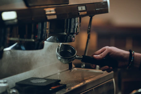 Close-up photo of a barista demonstrating espresso extraction with a manual espresso machine.