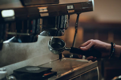 Close-up of hands skillfully preparing espresso with a professional machine in a cozy café setting.