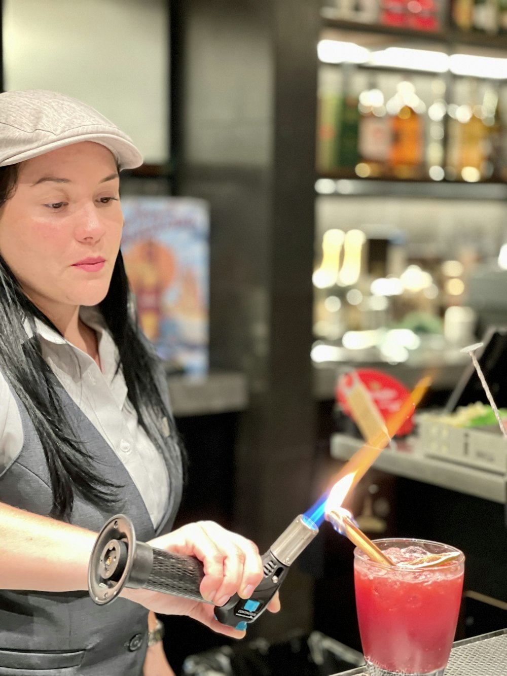 a woman holding a pencil and a glass of red liquid