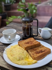 A rustic wooden table set with breakfast dishes and coffee.