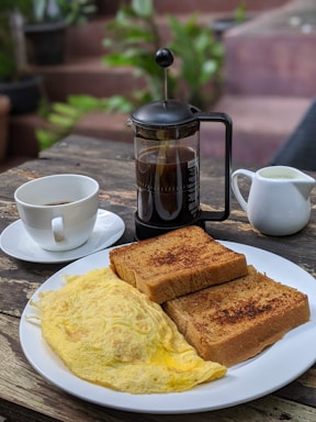 A rustic wooden table set with breakfast dishes and coffee.