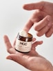 a hand holding a jar of peanut butter
