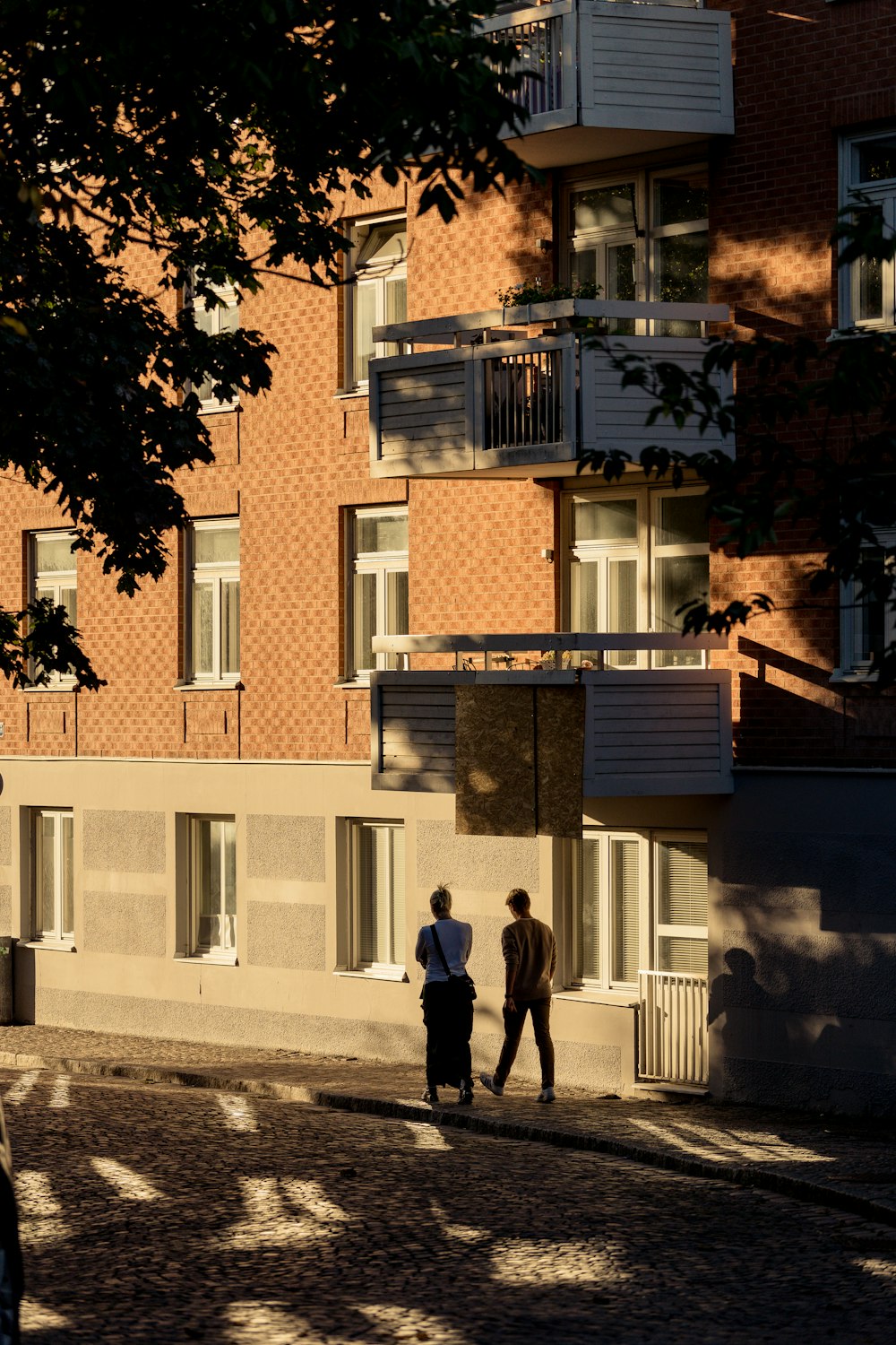 a couple of men walking down a street in front of a building