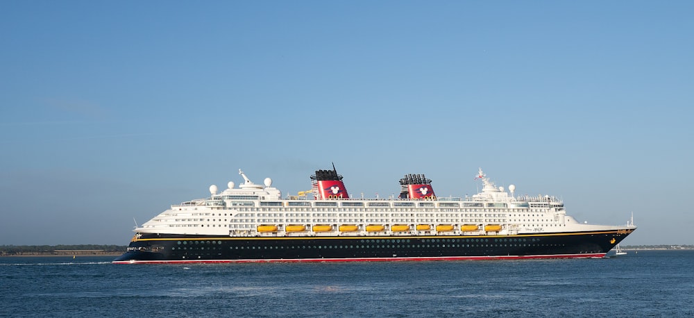 a large cruise ship on the water with RMS Queen Mary in the background