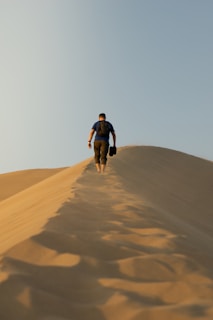 a man walking up a sand hill