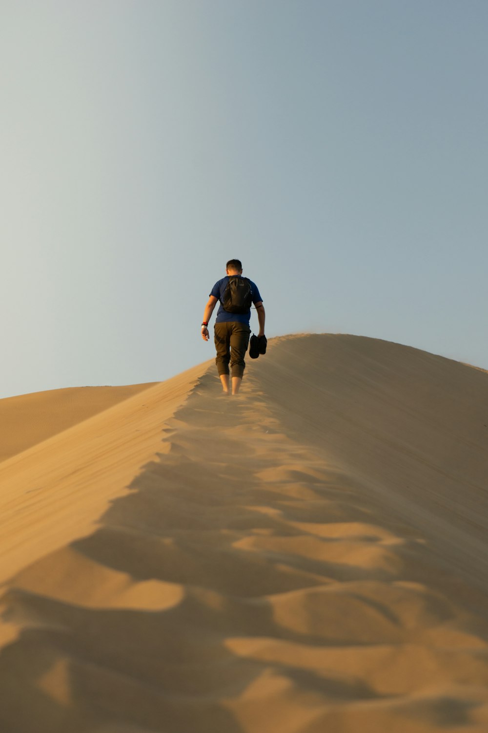 Un hombre subiendo una colina de arena
