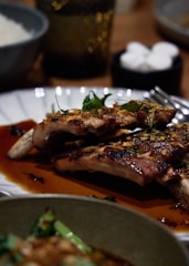 A close-up of a sizzling rack of ribs glazed with rich barbecue sauce, surrounded by rustic wooden serving boards.