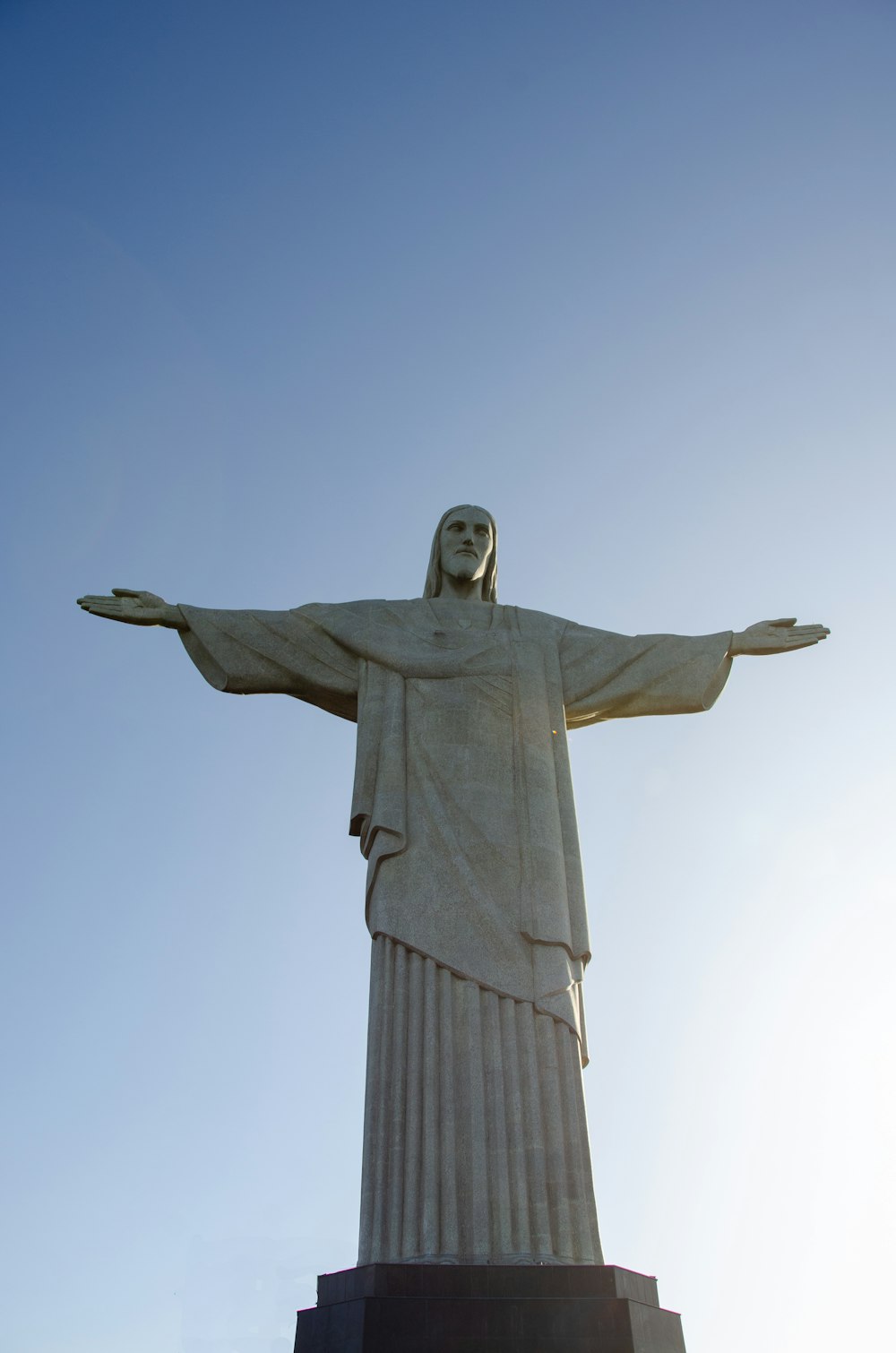 una estatua de una persona con Cristo Redentor al fondo