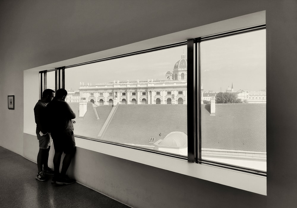 a couple of people looking out a window at a city