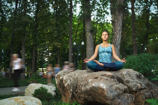 A serene woman sitting cross-legged outdoors, eyes closed, embodying calm and presence.