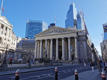a large building with columns and a statue in front of it with Royal Exchange, London in the background