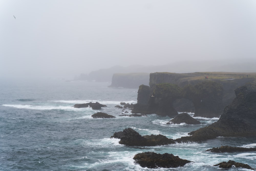 a rocky beach with a body of water in the background