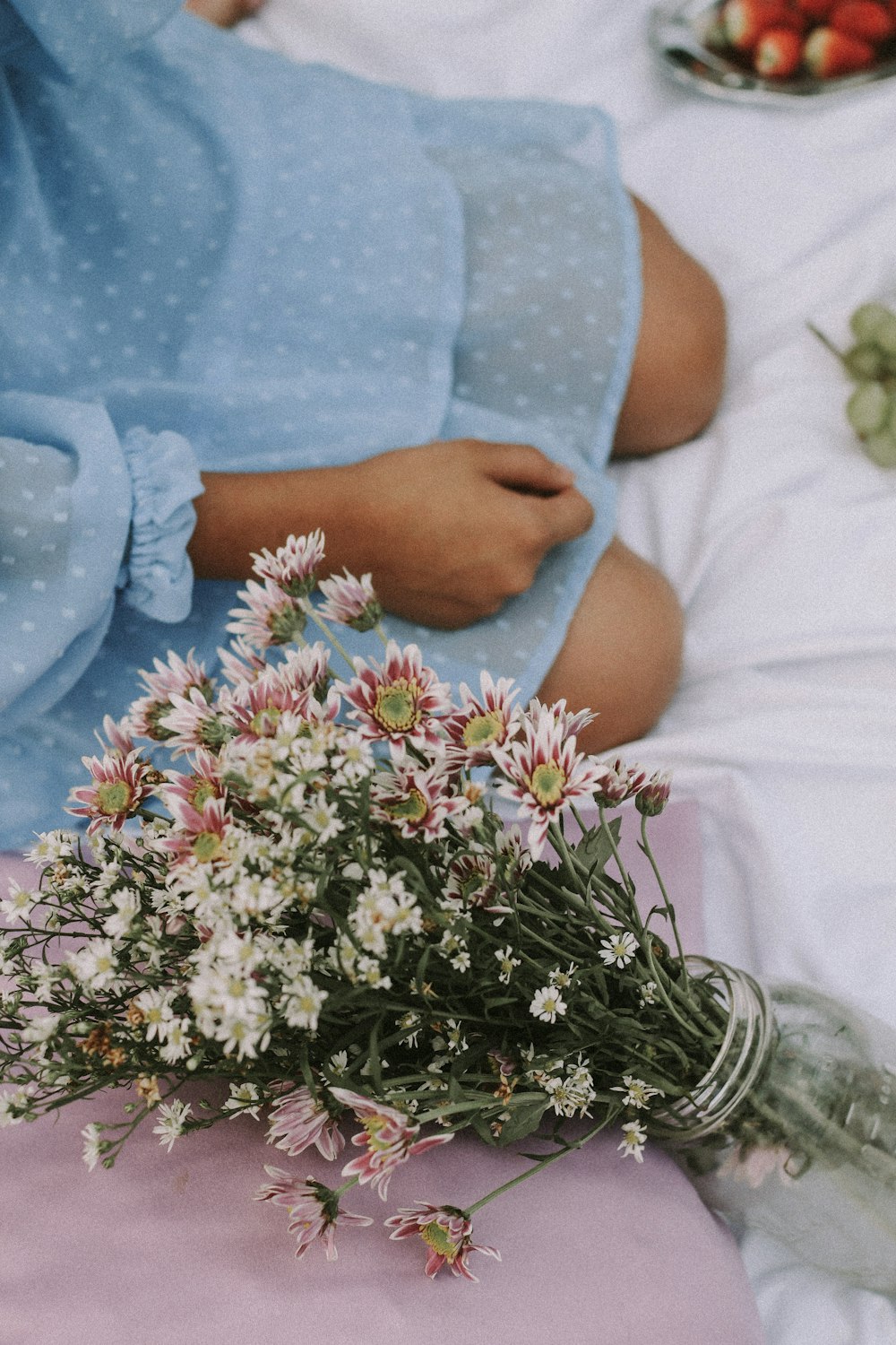 a person lying on a bed with flowers on the stomach