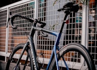 Close-up of a sleek gravel bike leaning against a rustic wooden fence.